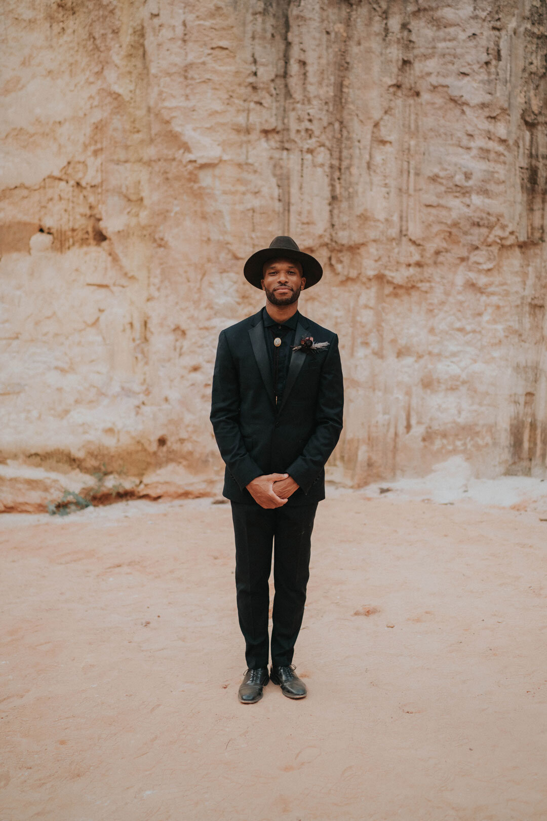 Black groom in black suit and hat