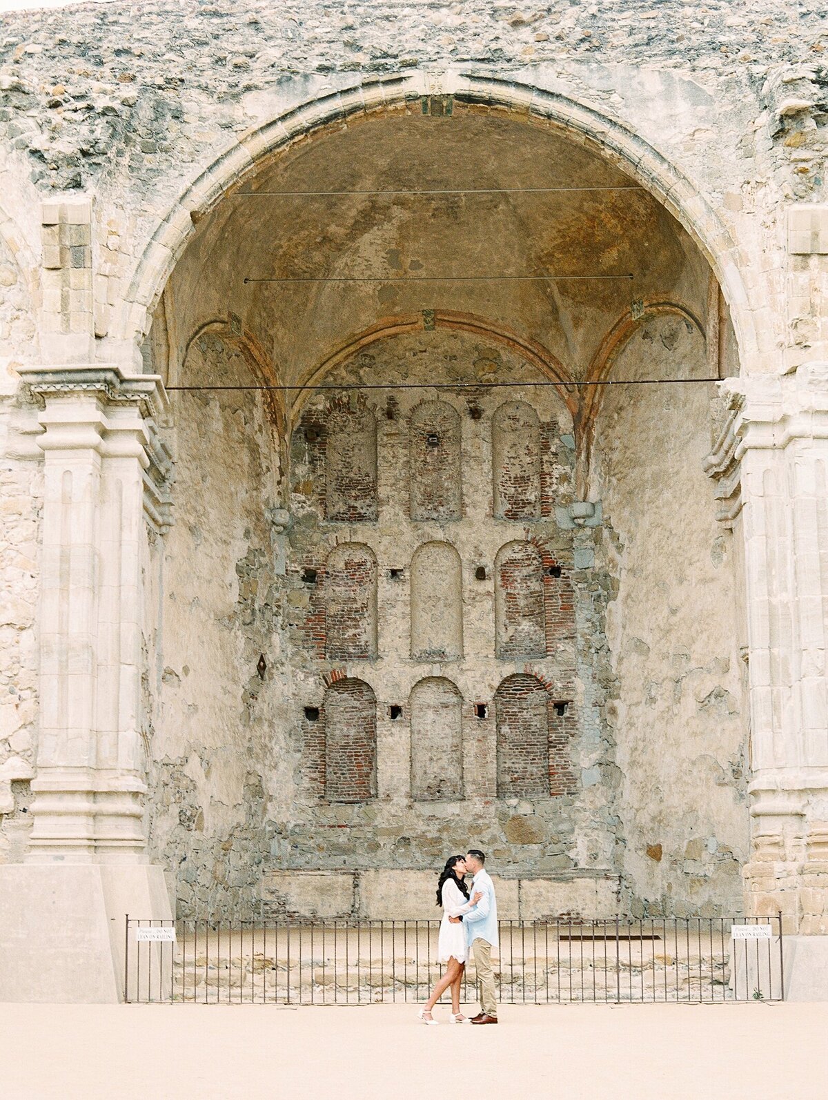 Couple kissing at the Mission San Juan Capistrano by Film and Digital Photographer, Lisa Riley.