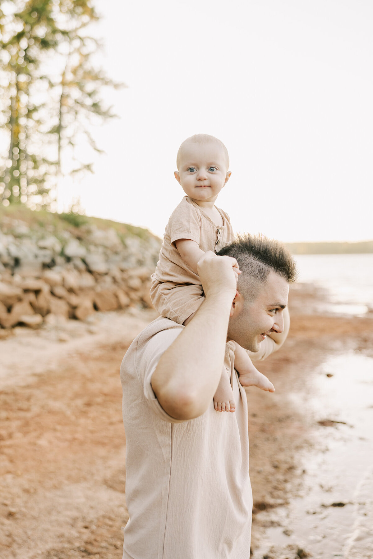 Baby boy riding on the shoulders of his dad during their family session