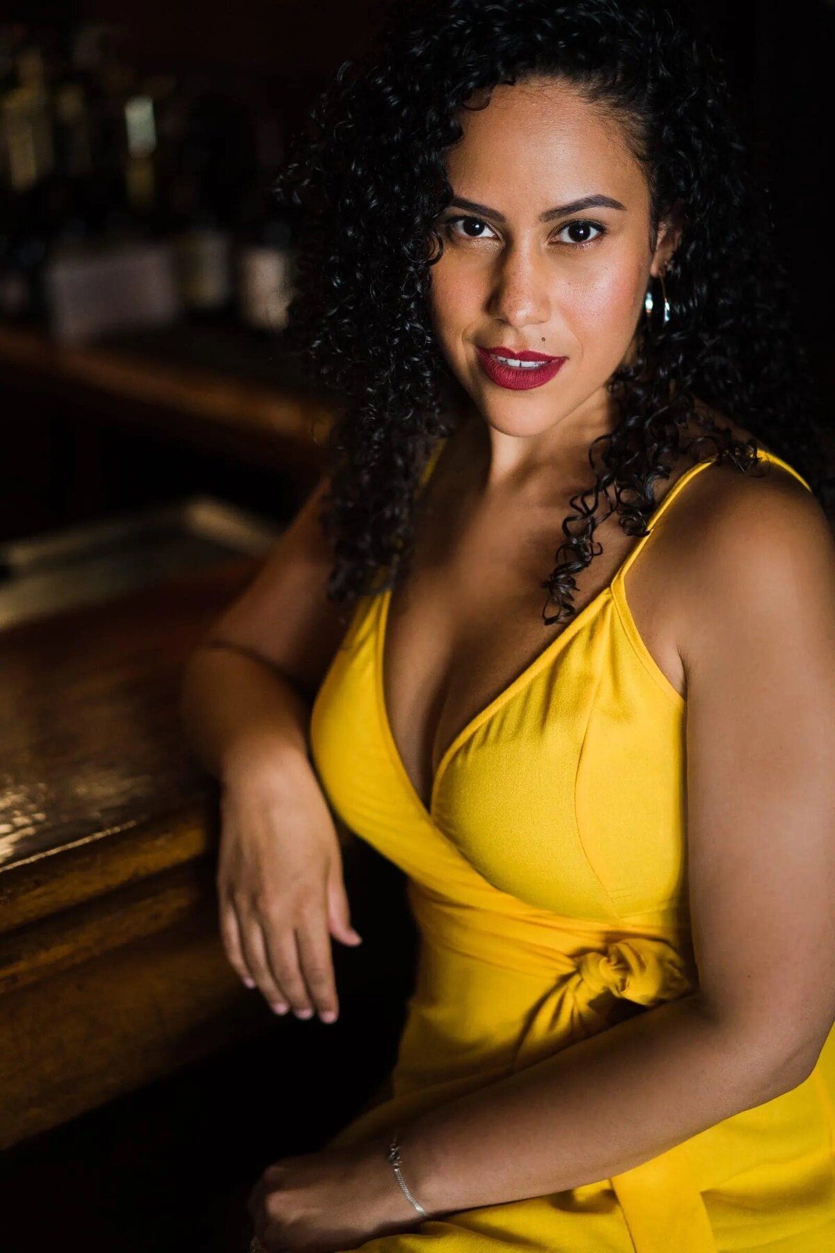 A woman in a dress sitting and leaning on a table