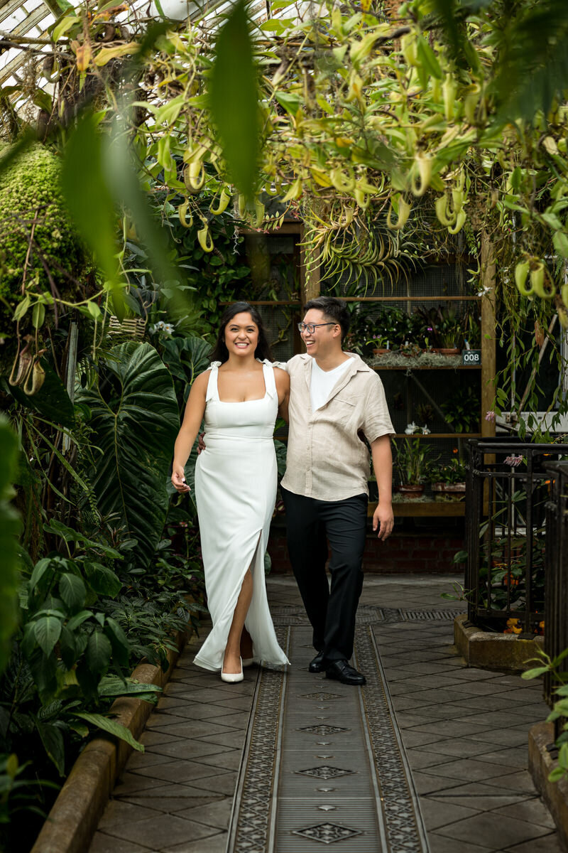 This engagement session captures a sweet and playful moment as the couple strolls through the vibrant, plant-filled paths of the Conservatory of Flowers in San Francisco. With the natural greenery and exotic plants hanging overhead, this scene feels intimate and connected to nature. The couple's relaxed, happy expressions reflect the love and excitement they share, making this a perfect backdrop for their engagement photos. The unique setting highlights the natural beauty surrounding them while still allowing their personalities to shine through.