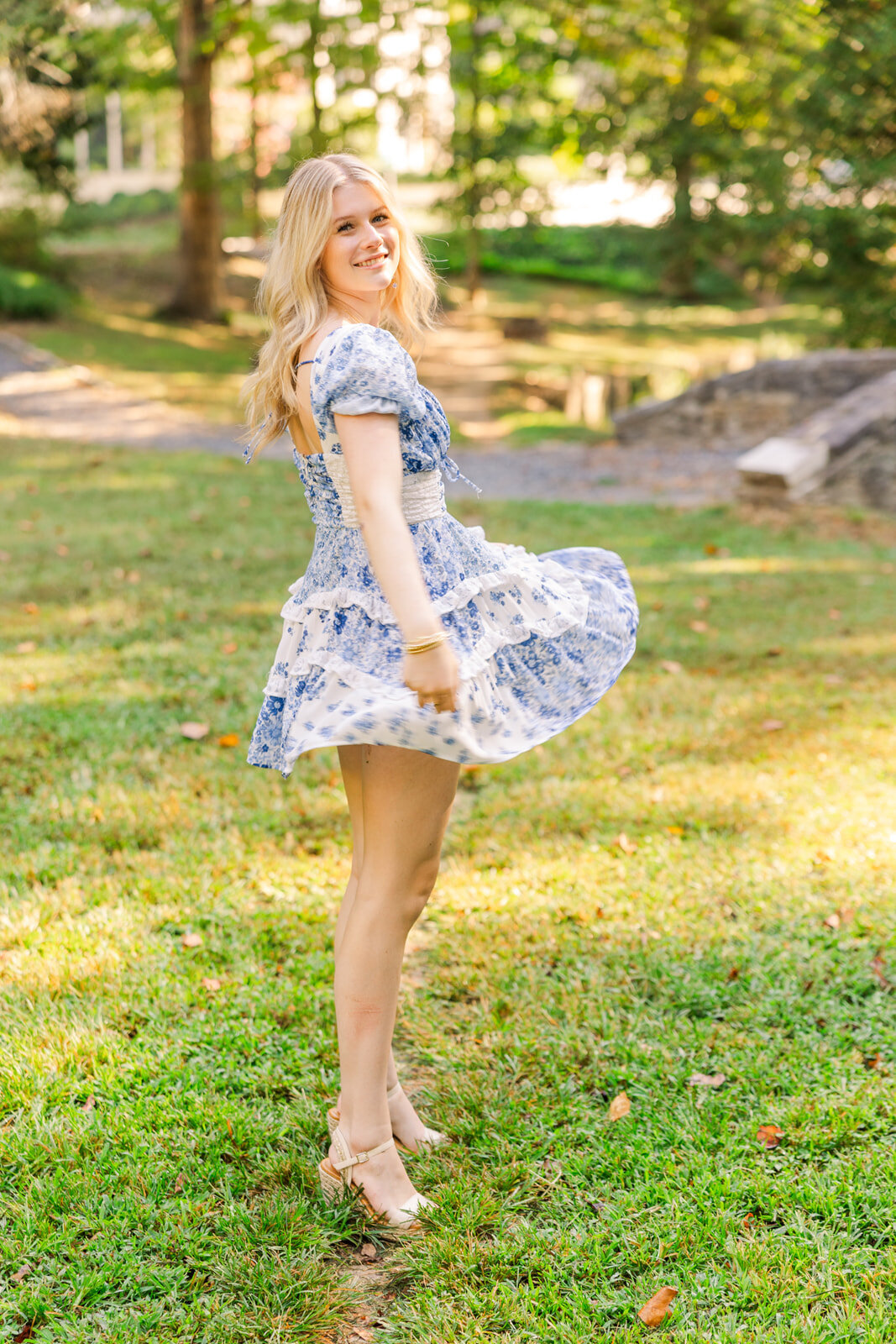 high school girl wearing blue and white short dress spinning in a park Atlanta