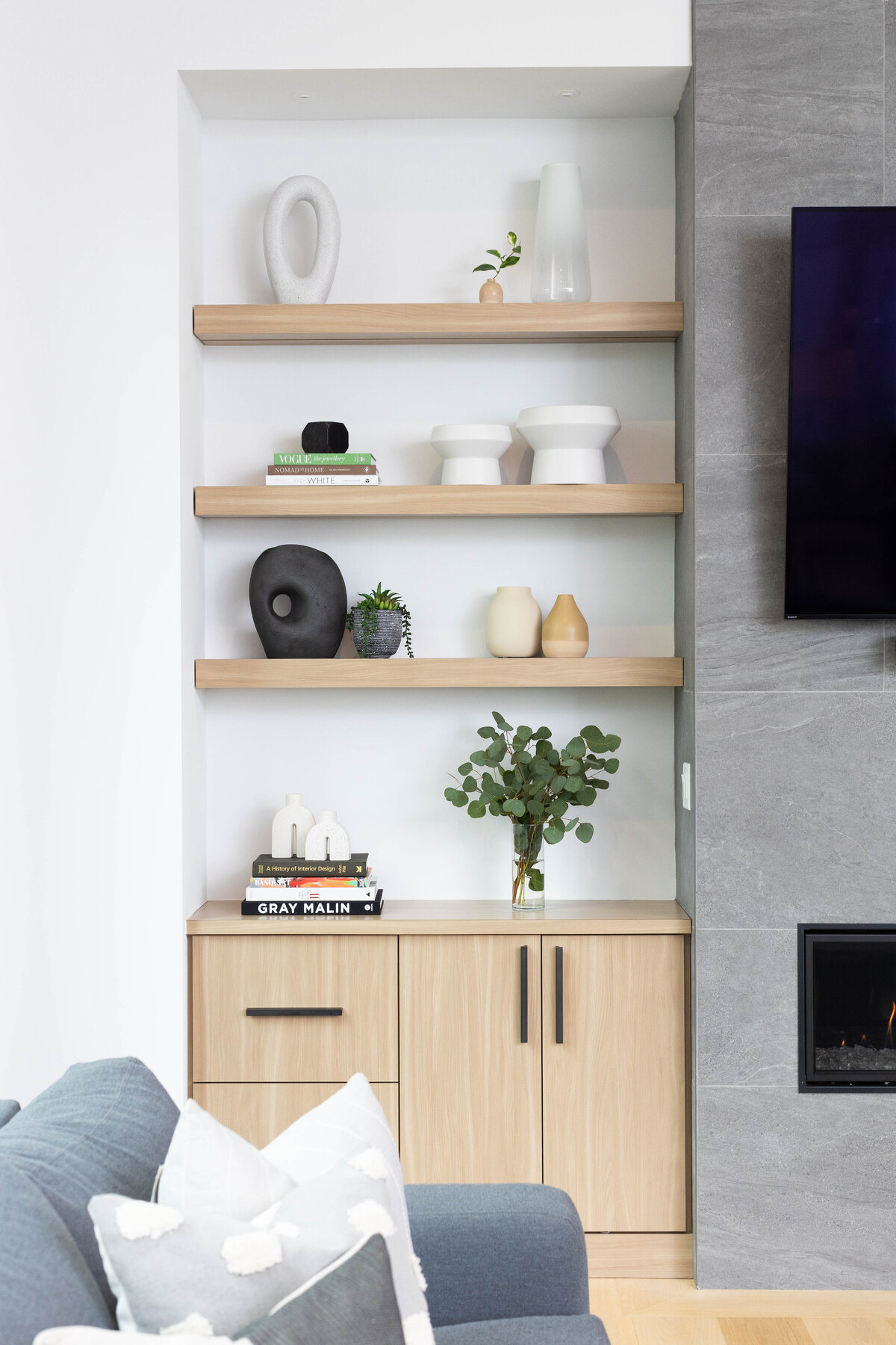 corner of a modern livingroom with birch shelving