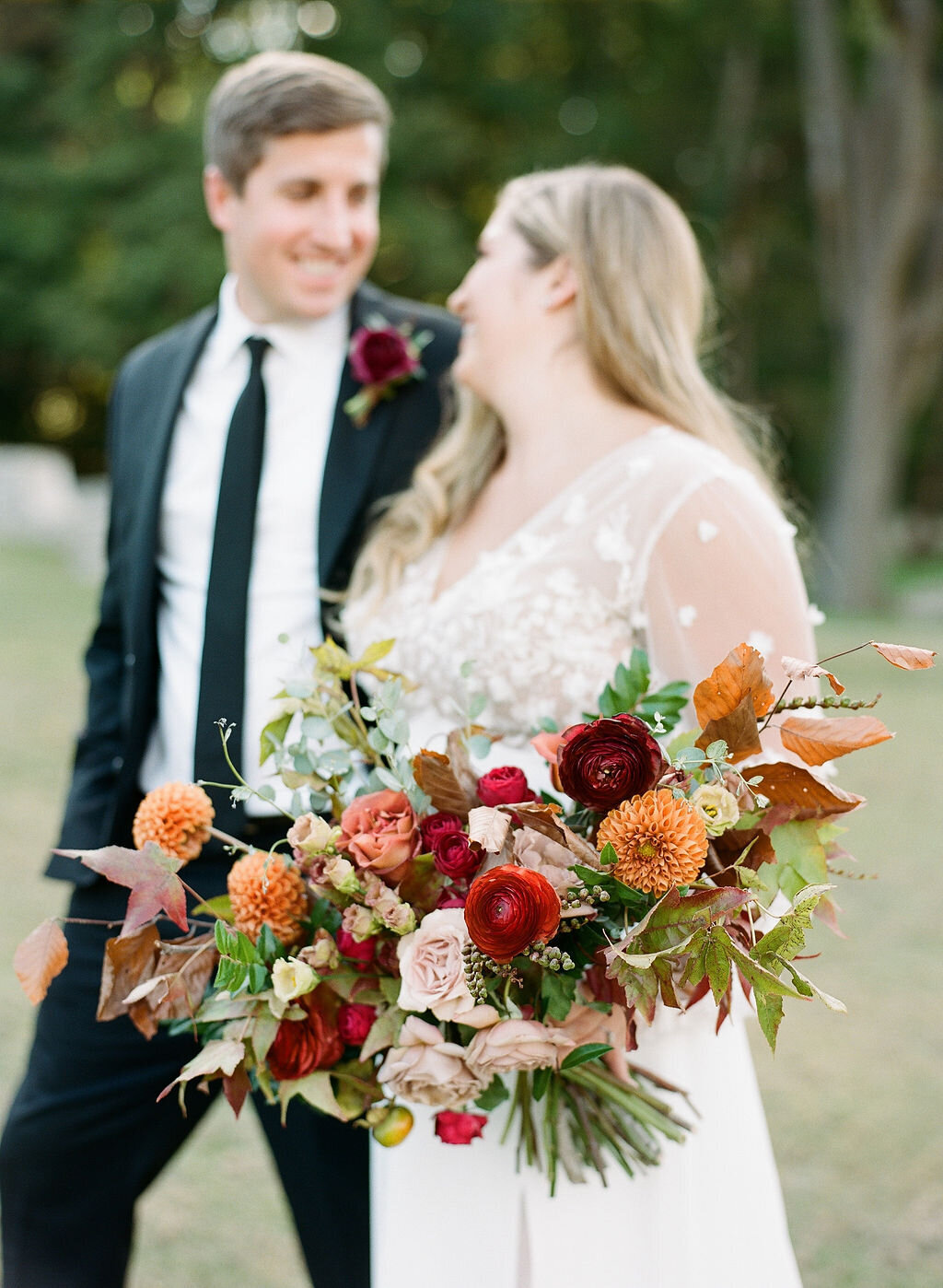 A whimsical bridal bouquet filled with burgundy, terra cotta, dusty rose and burnt orange florals. The bouquet features ranunculus, garden roses, dahlias, fruiting branches and autumn foliage. Designed by Rosemary and Finch in Nashville, TN.