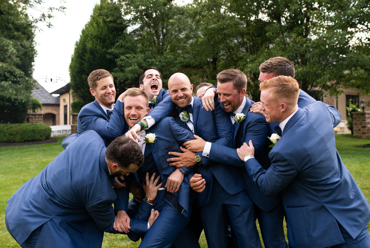 Groomsmen tackle the groom during pre-ceremony portraits