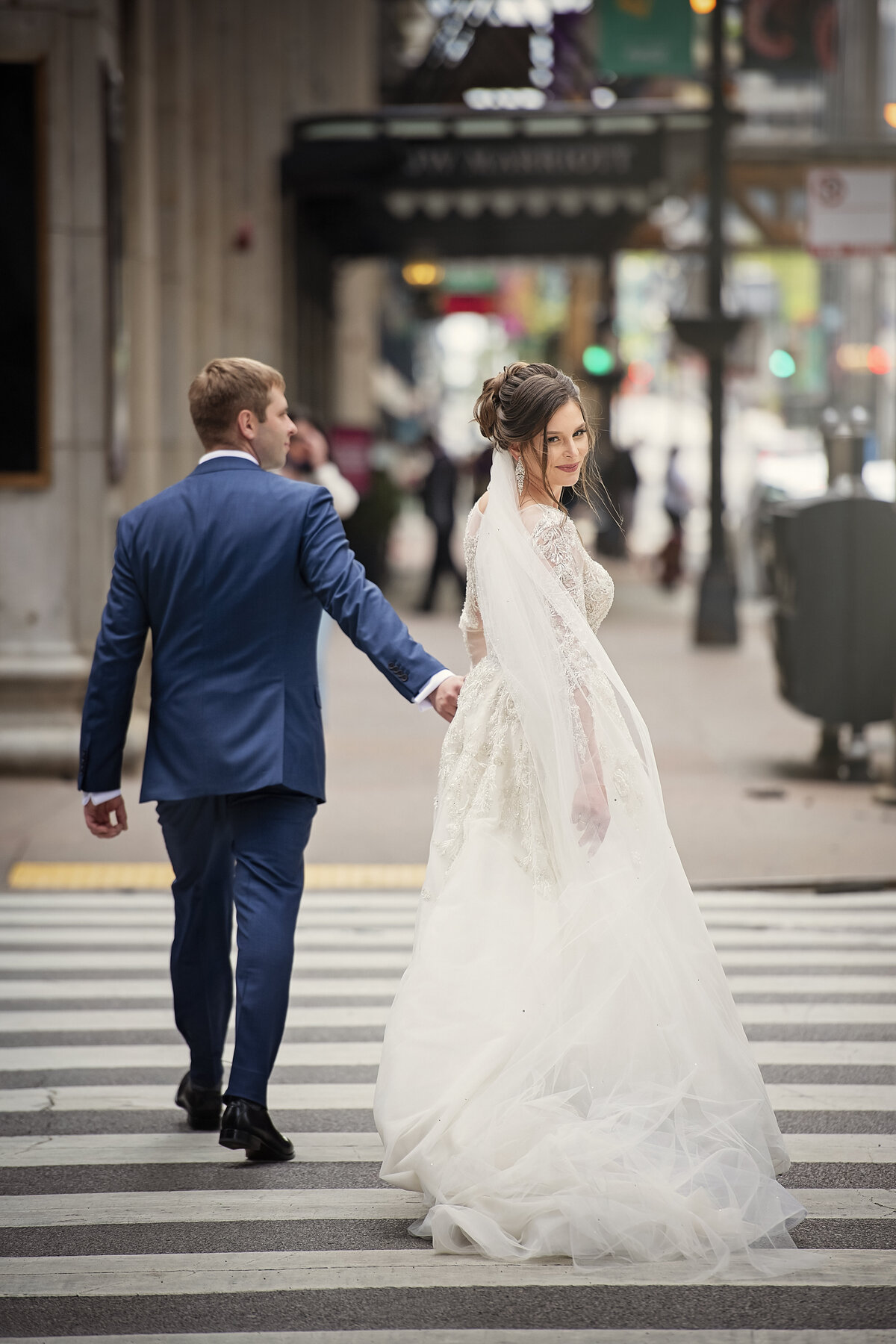 bride and groom  crossing busy street of Chicago while holding hands