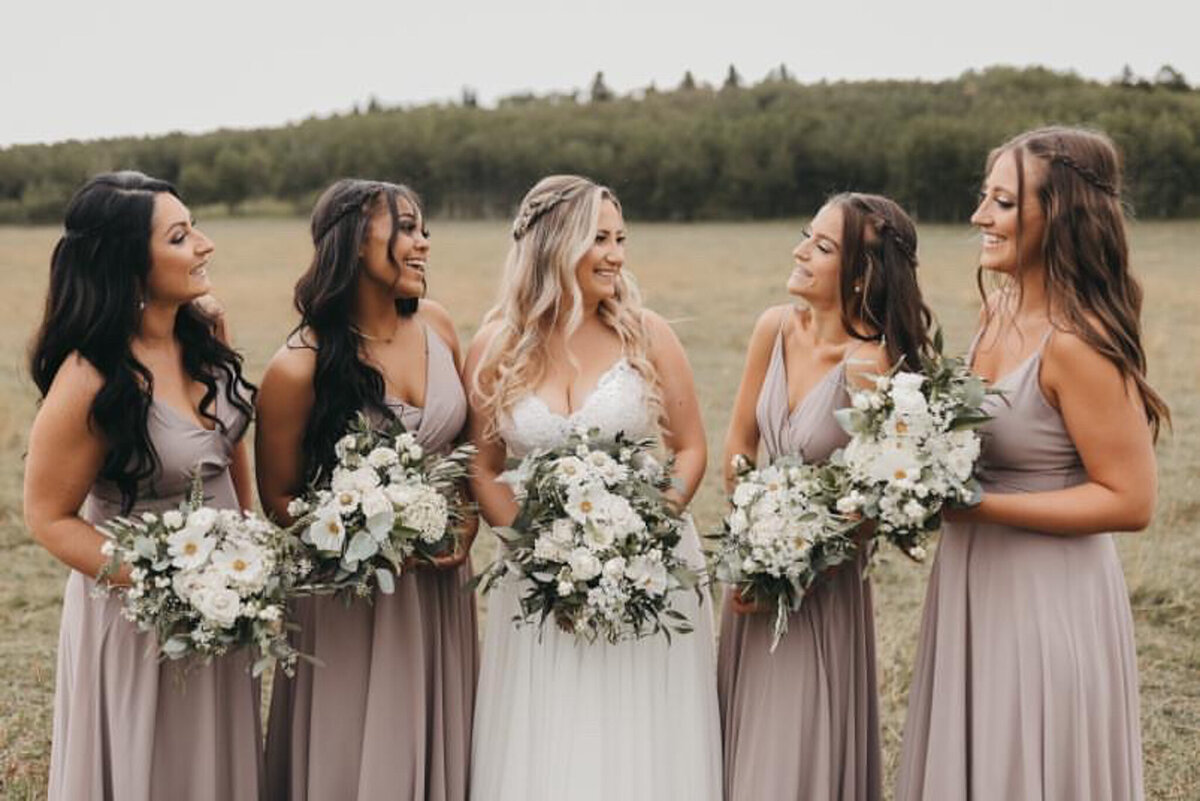 Bridesmaids holding stunning and elegant white bouquets by Flowers By Janie, artful Calgary, Alberta wedding florist, featured on the Brontë Bride Vendor Guide.
