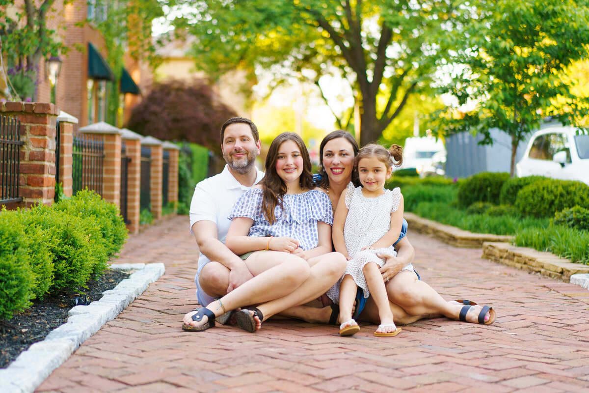 Family of four sits together on a brick sidewalk in German Village in Columbus, Ohio.