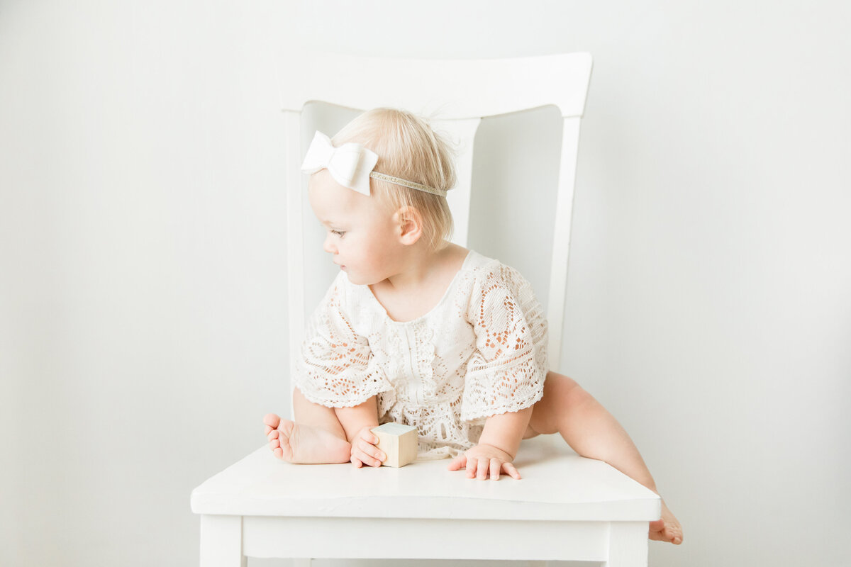 little girl in boho outfit with bow sitting on chair