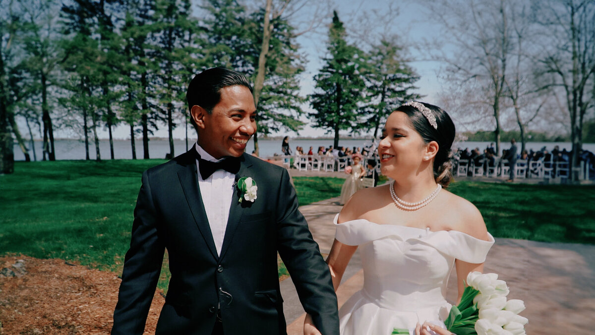 bride and groom walking down outdoor aisle smiling at eachother