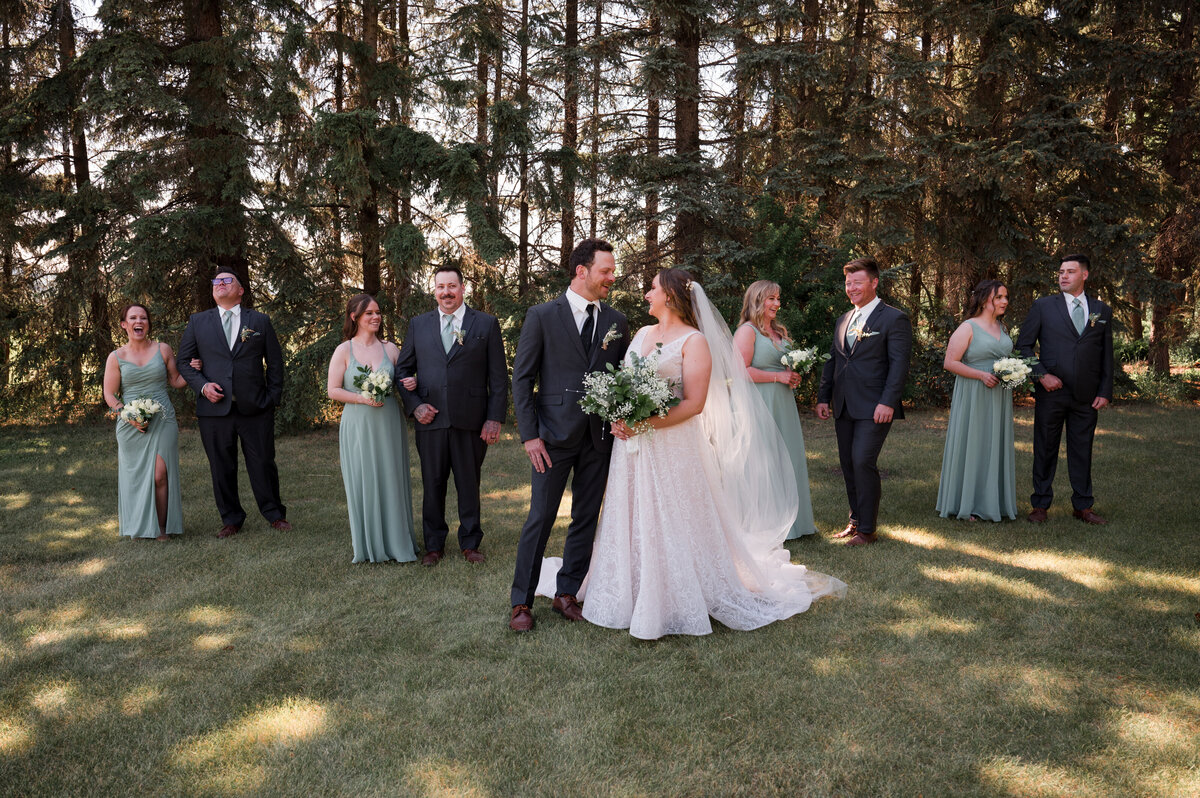 bride and groom stand kissing, while wedding party runs around them creating an artisic wedding portrait with movement