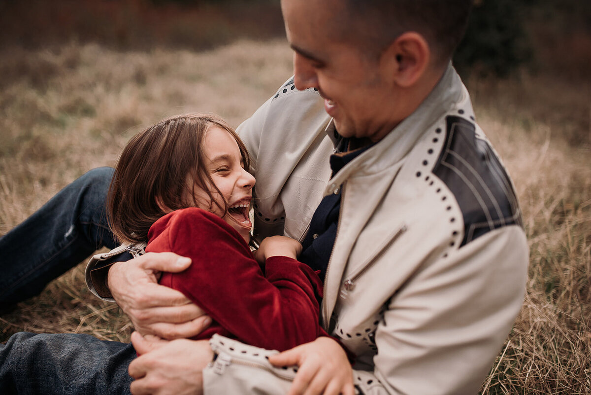 Dad holds laughing little boy in his arms