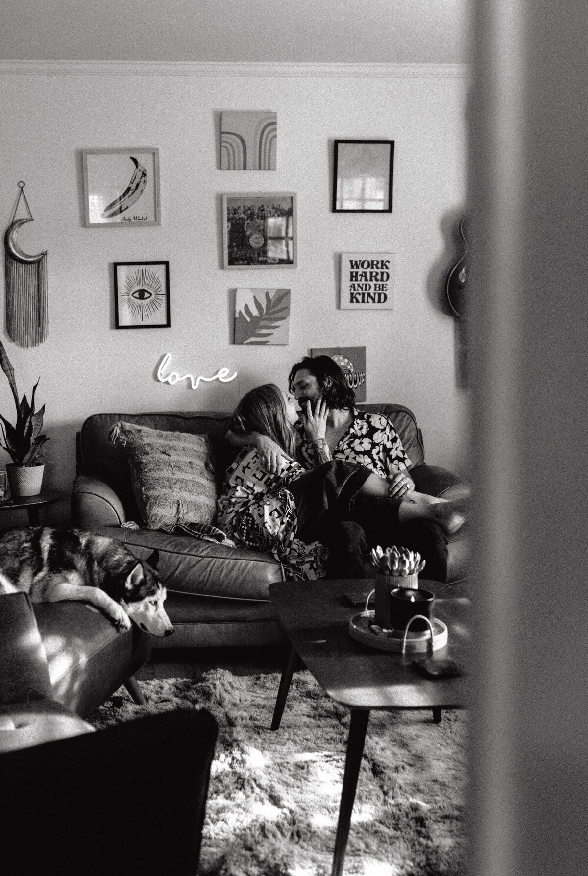 couple kissing & snuggling on couch during in -home engagement session in panama city