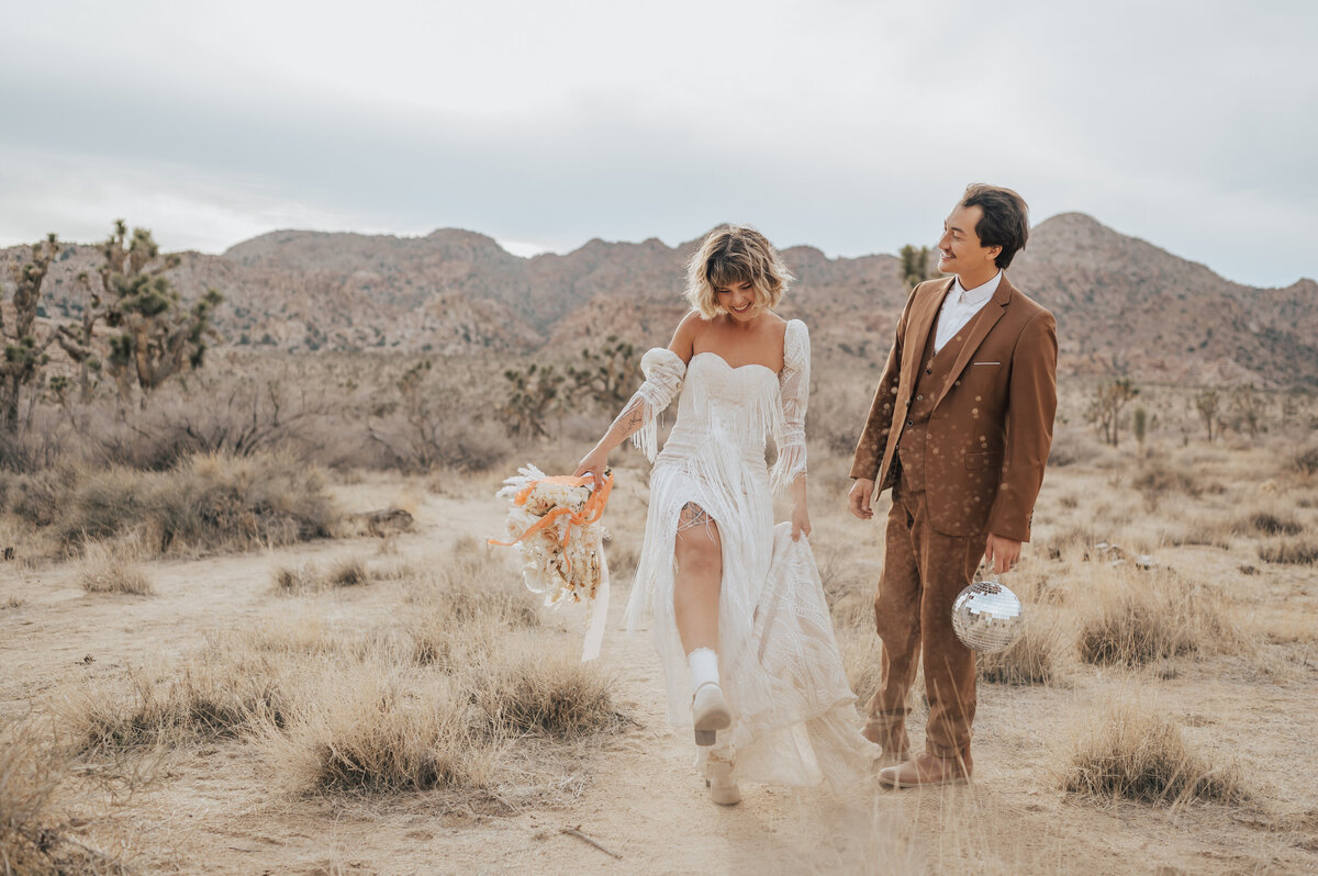 newlyweds walk in desert with disco ball