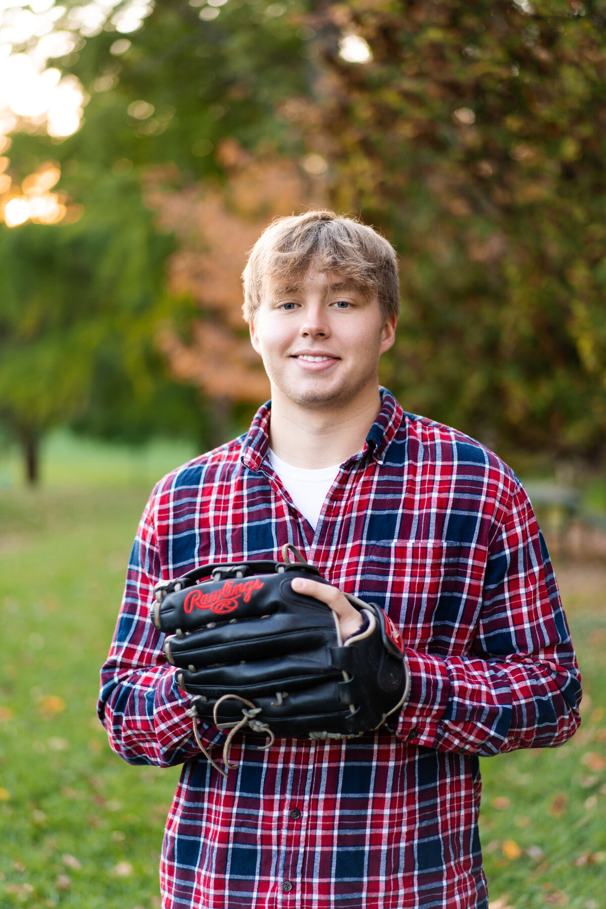 Senior Jacob Kowalczyk poses with a baseball glove in front of colorful trees at Jeffrey Mansion in Columbus Ohio.
