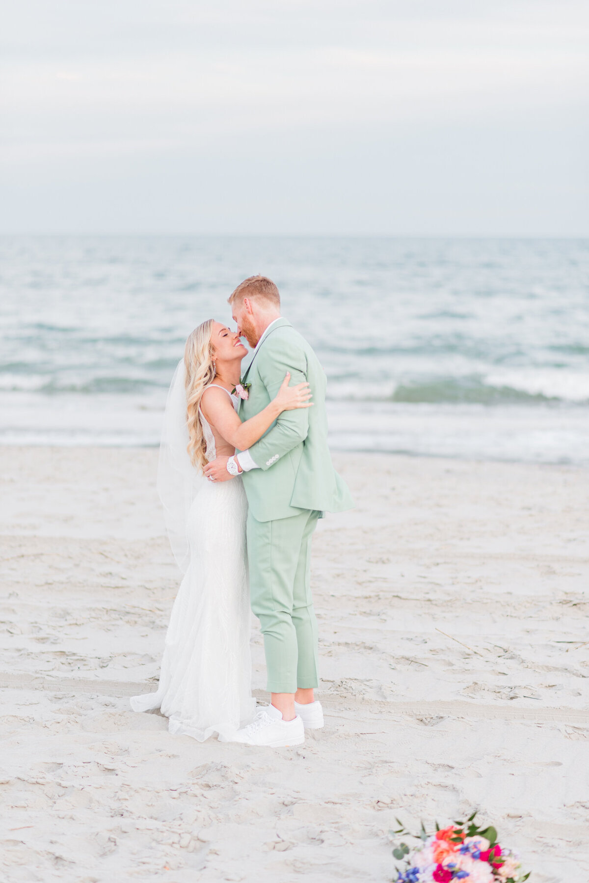 bride and groom kissing on the beach in wilmington, nc