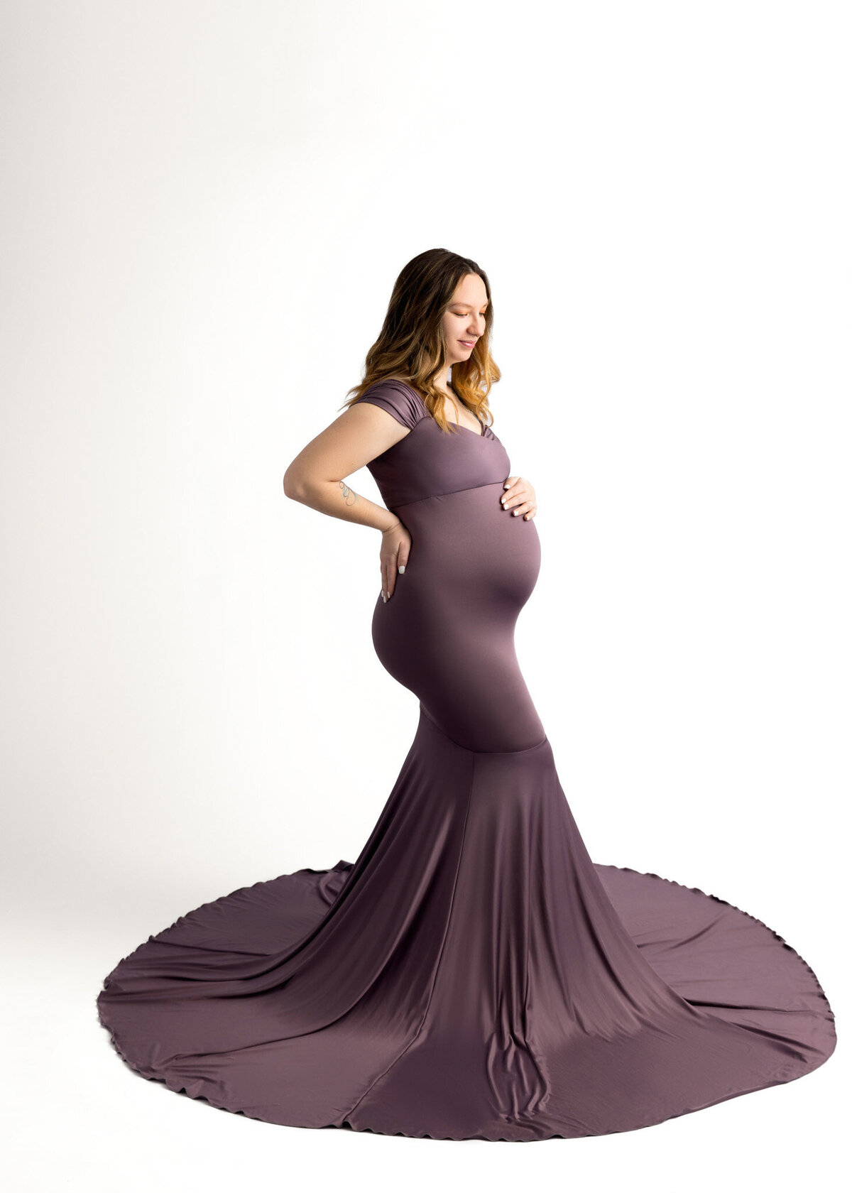 prenant woman with her hand on her belly wearing a purple dress