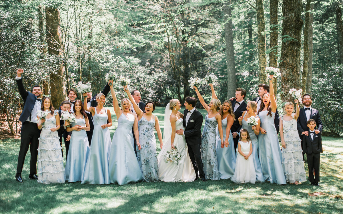 Bride and groom celebrate with bridesmaids in light blue dresses and groomsmen in tuxedos in the garden at Old Edwards Inn in Highlands, North Carolina.