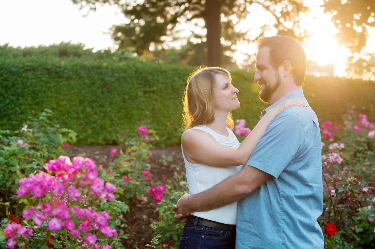 a couple look at each other surrounded by pink flowers and sunlight