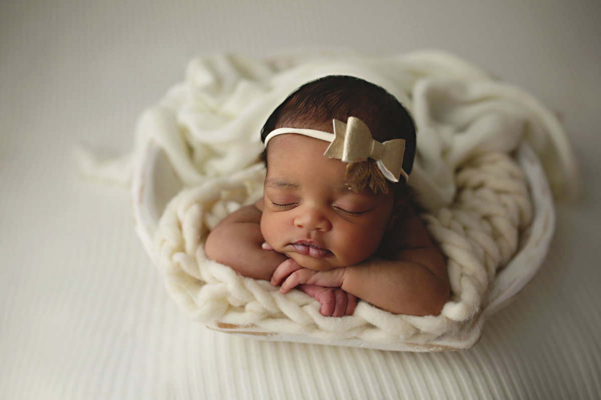 black newborn baby with metallic gold bow on head