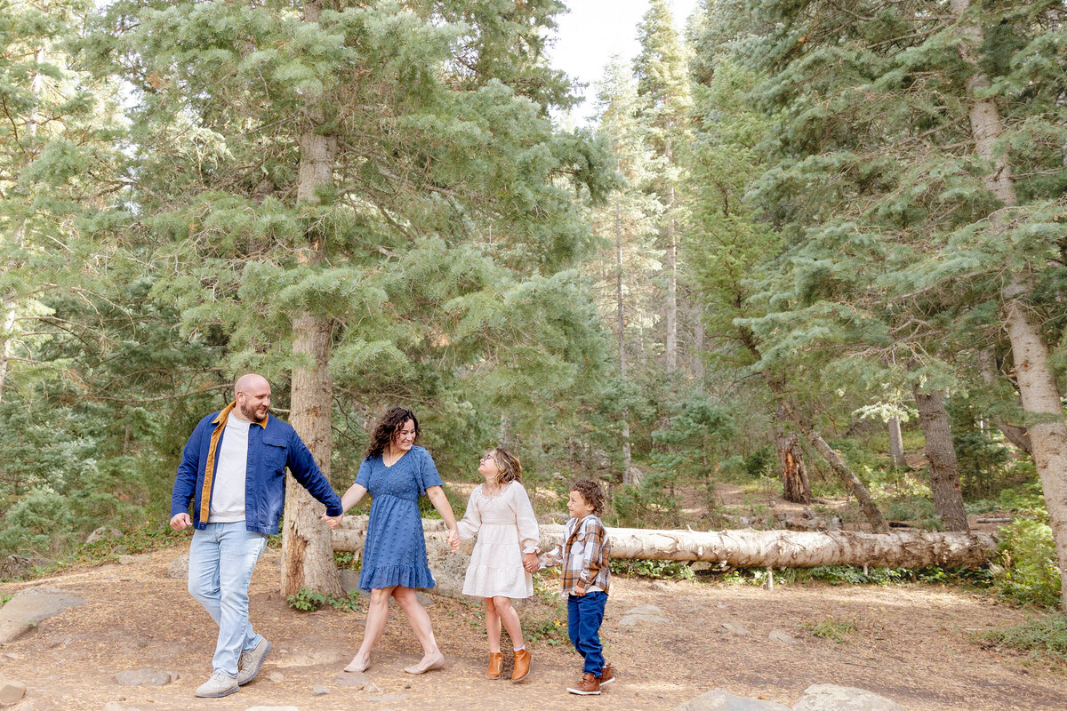 A family of four walks hand in hand along a scenic wooded trail at Tibble Fork Reservoir, enjoying nature and quality time together in the fresh mountain air.