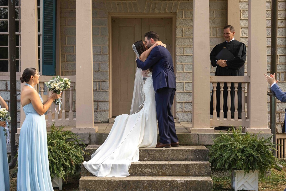 Bride and groom sharing first kiss at wedding alter