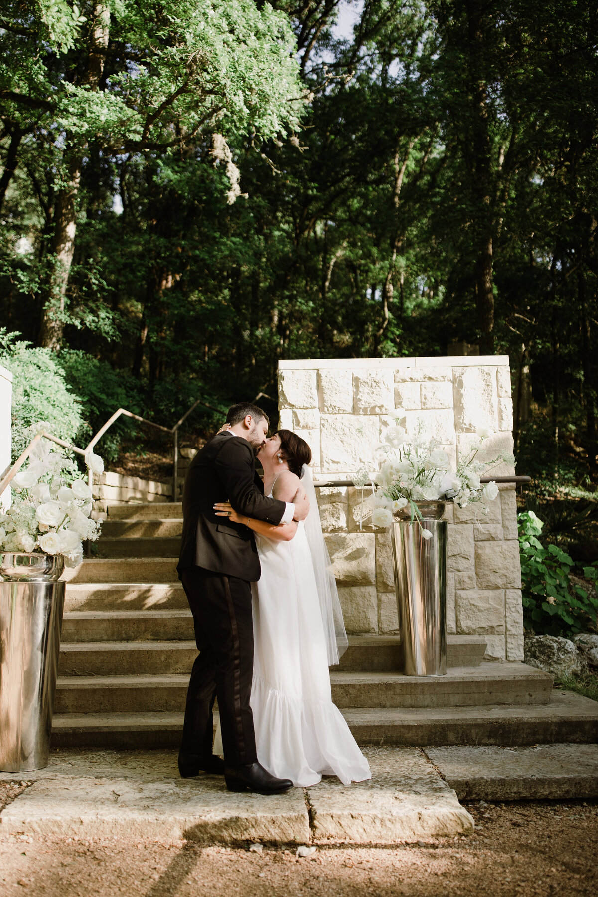 Bride and groom kissing at outdoor wedding ceremon y at Umlauf Sculpture Garden, Austin