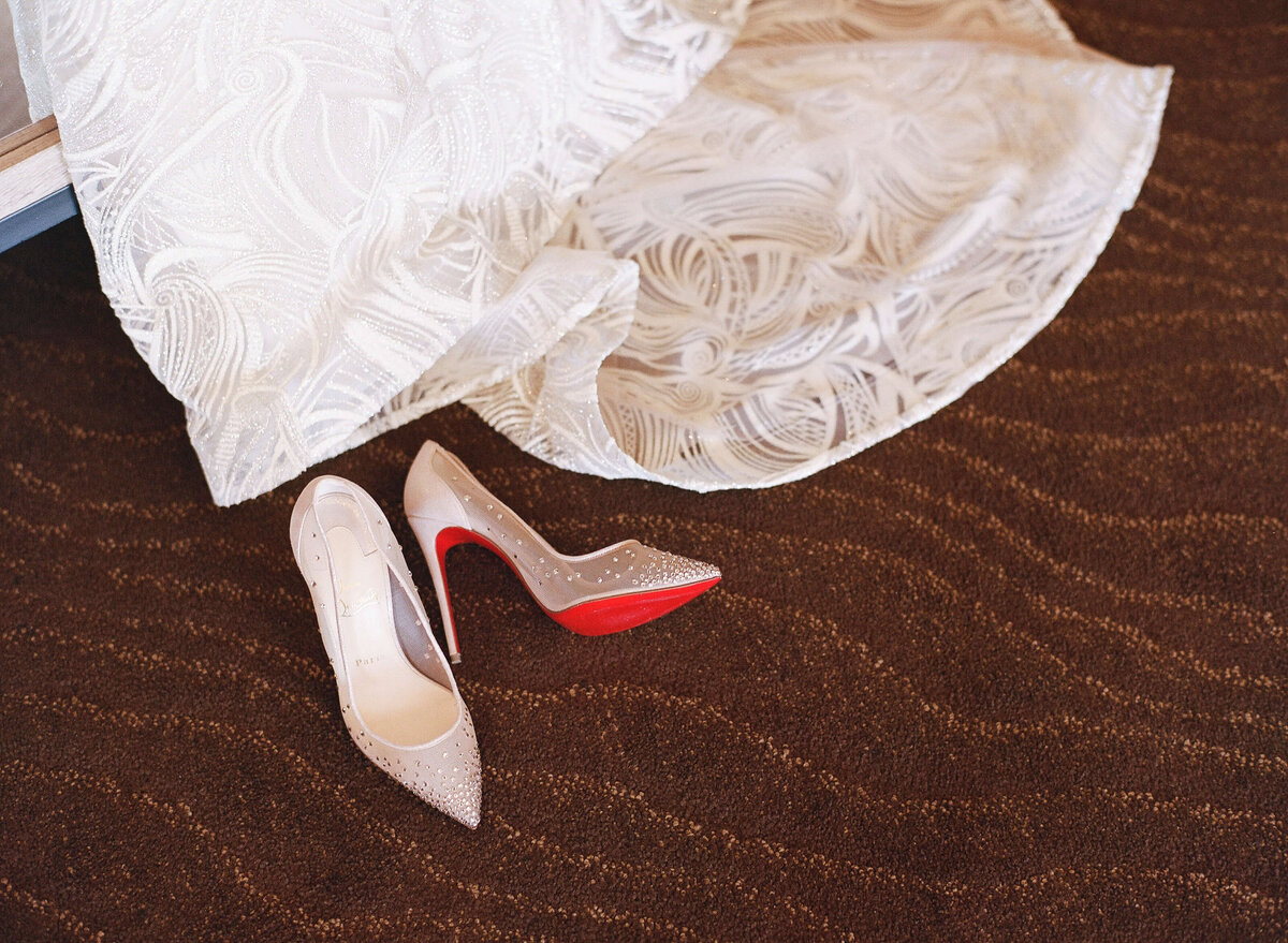 close up detail of louboutin shoes and wedding dress