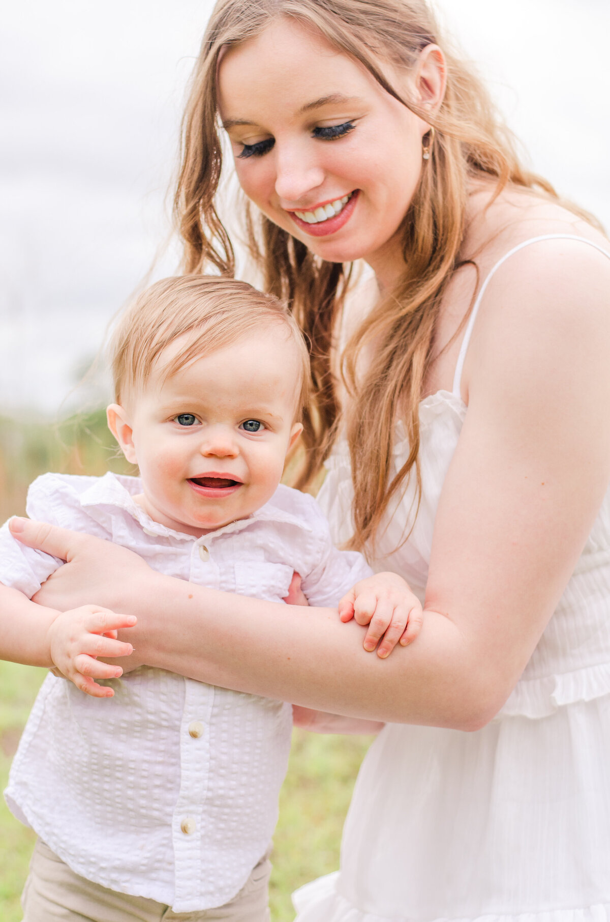 mom holds her baby boy up standing