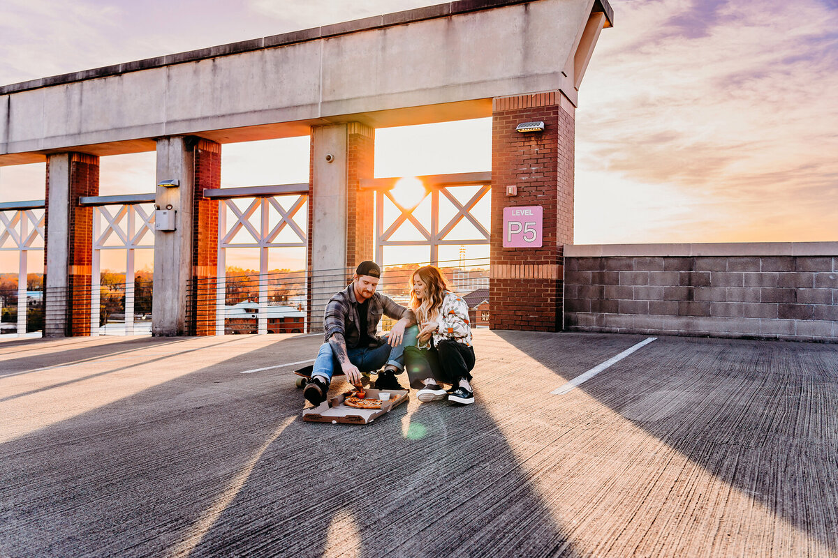 a couple enjoying pizza on skateboards on a tacoma parking garage rooftop