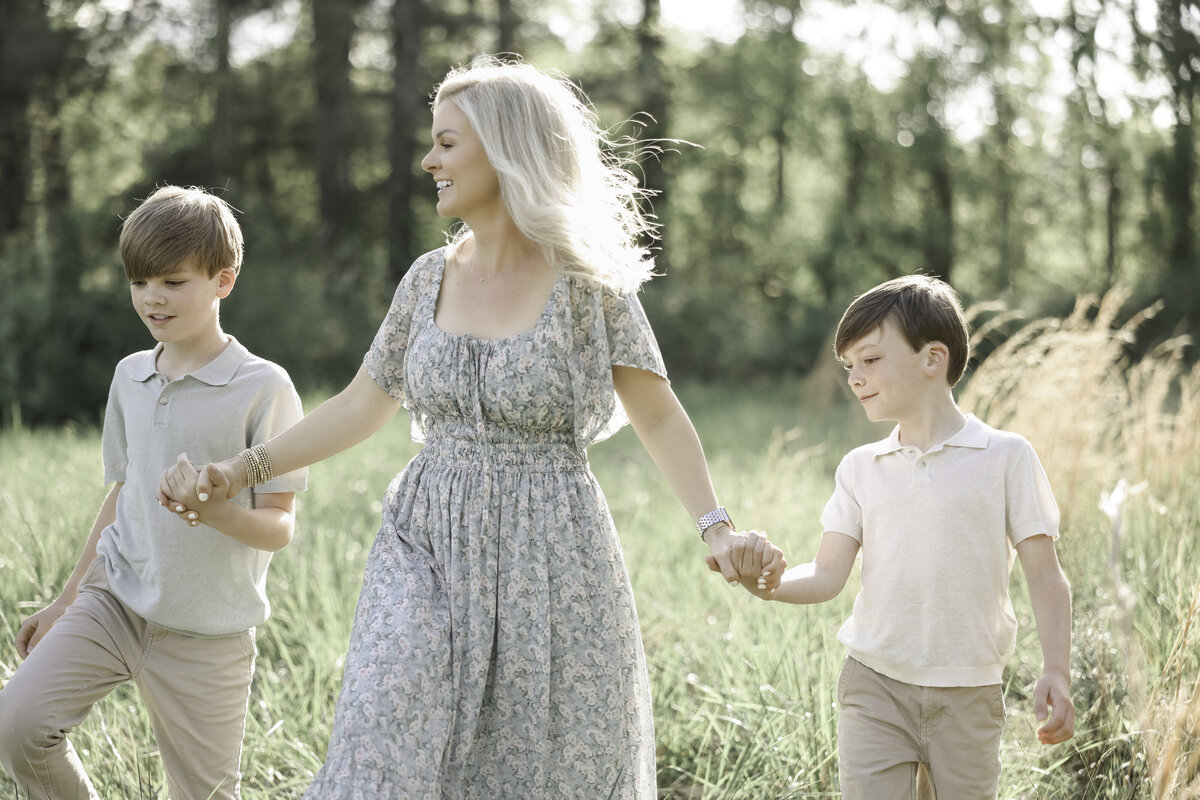 asheville family photographer mother and two sons walking in a field