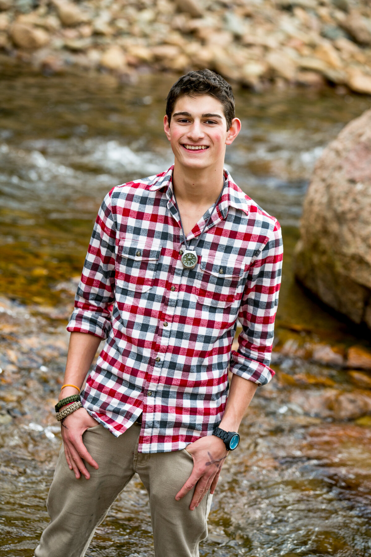 boy in plaid shirt stands near water
