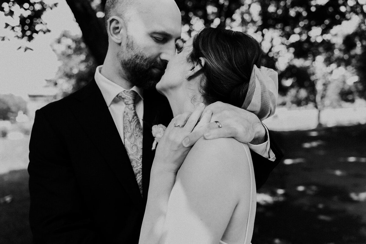 close up of couple kissing with holding fingers and focus is on wedding rings.