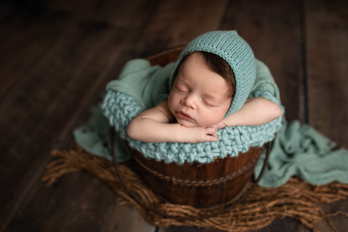 Baby boy posed in a brown water bucket.