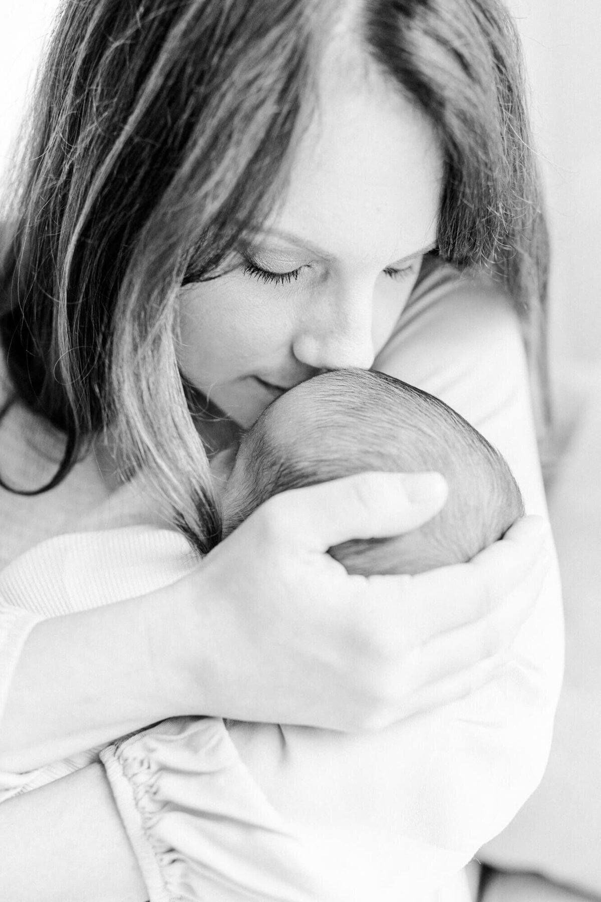 Black and white image of a mother snuggling her newborn