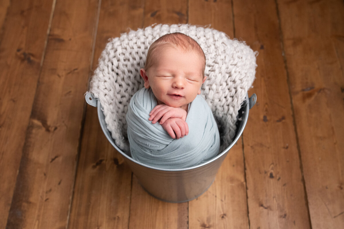 Happyily sleeping baby in silver bucket