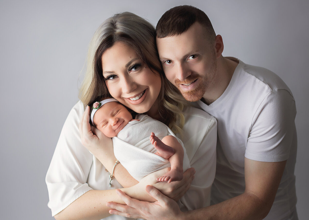 newborn baby girl smiling with parents