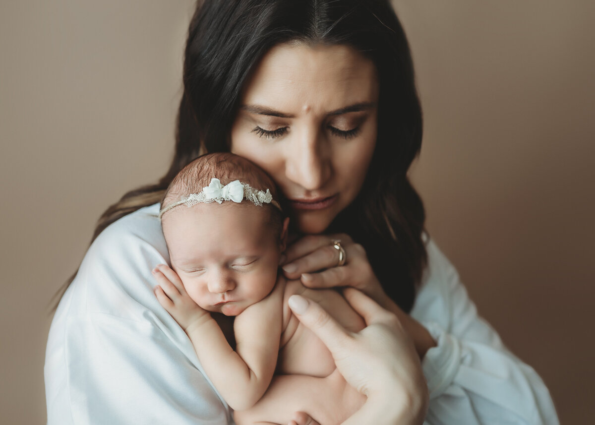 mother poses with newborn daughter for first photo in Denver Portrait studio