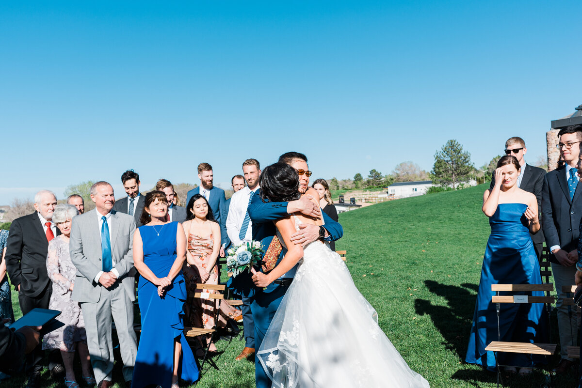 Denver wedding photographer KB Radiant photography captures a bride hugsging her father at the alter as she makes her way to the groom waiting for her