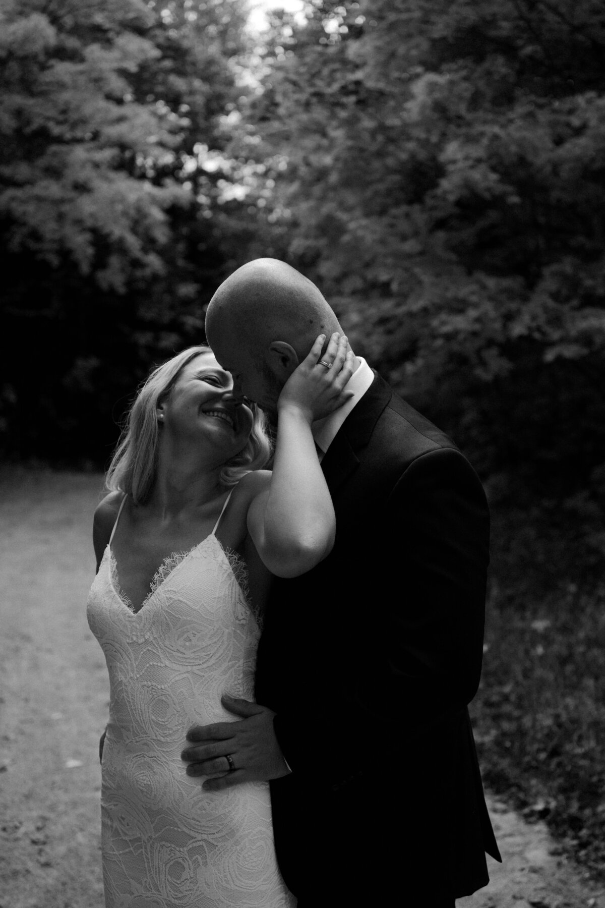 black and white image bride and groom kissing in woods