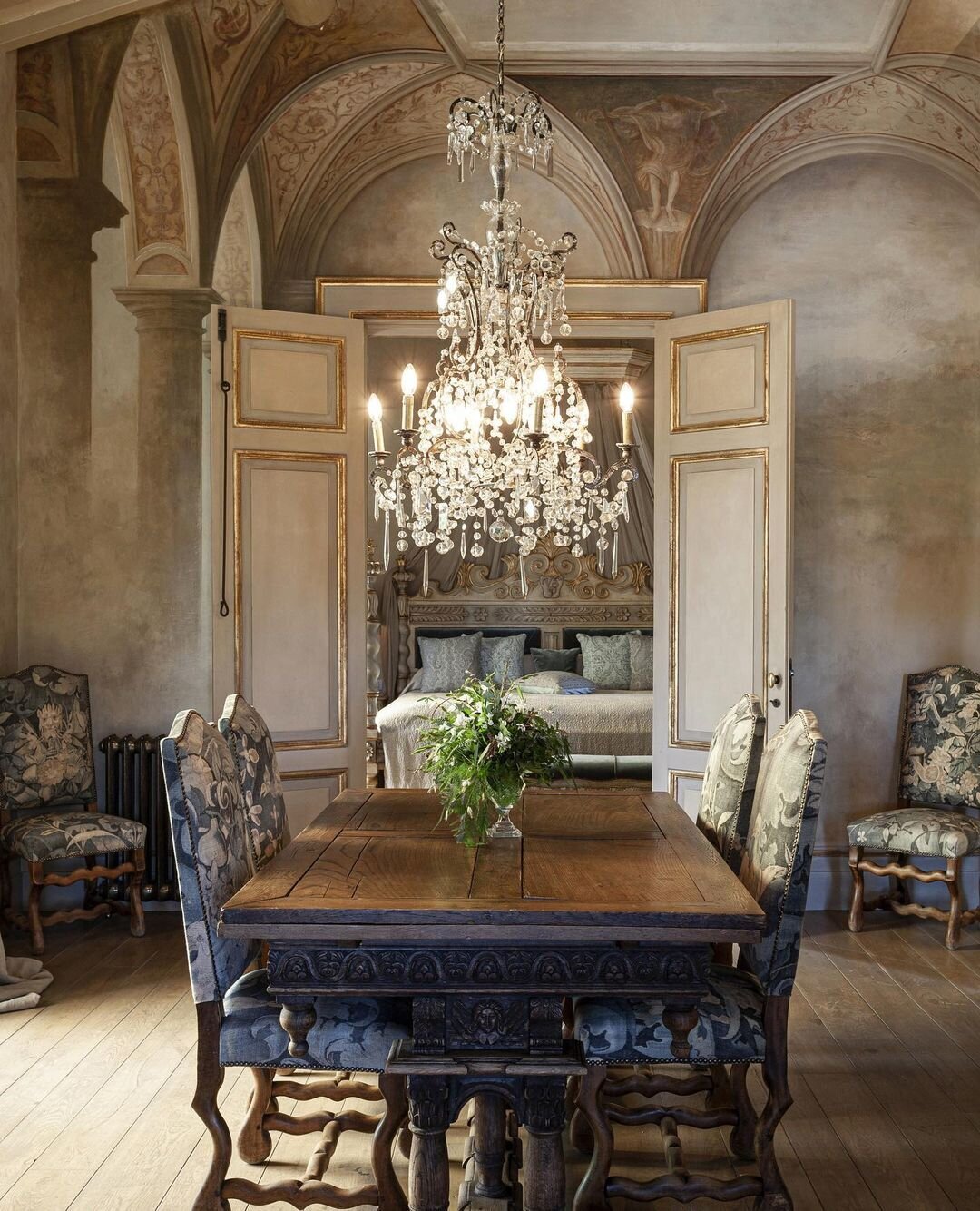 An antique wooden dining table surrounded by dining chairs upholstered in floral fabric at Borgo Santo Pietro