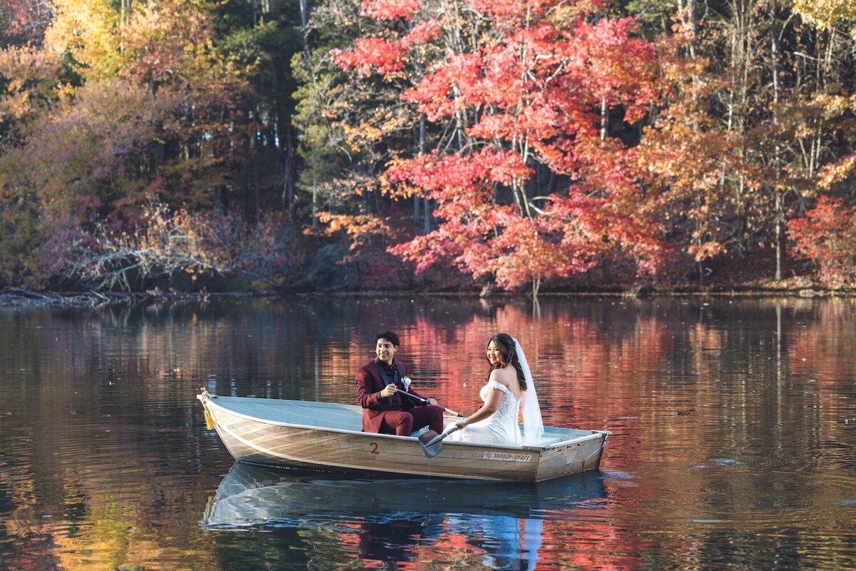 Groom helping bride into vintage rowboat on lake