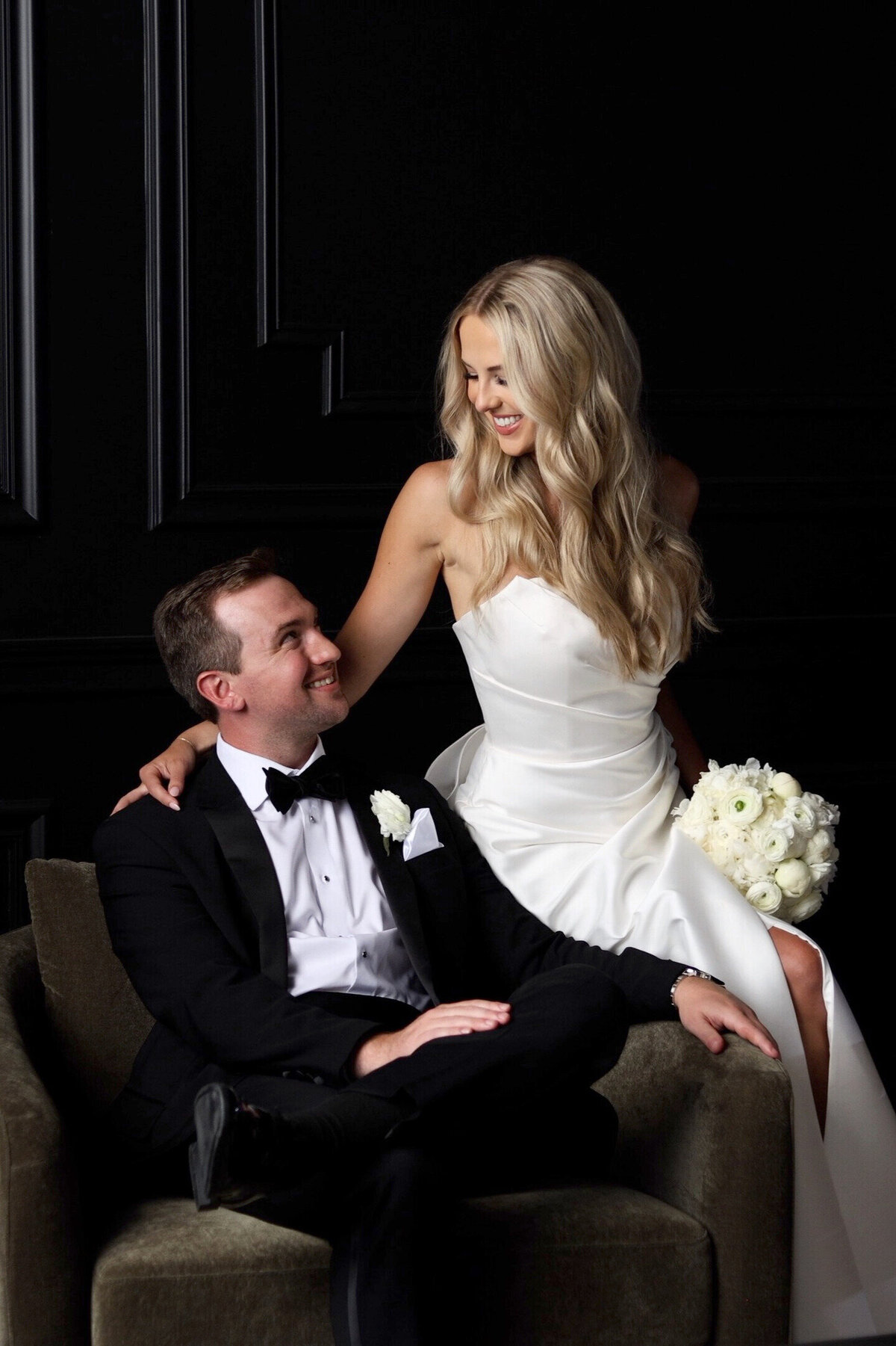 Bride sitting on groom's chair, smiling at each other at The Century Club