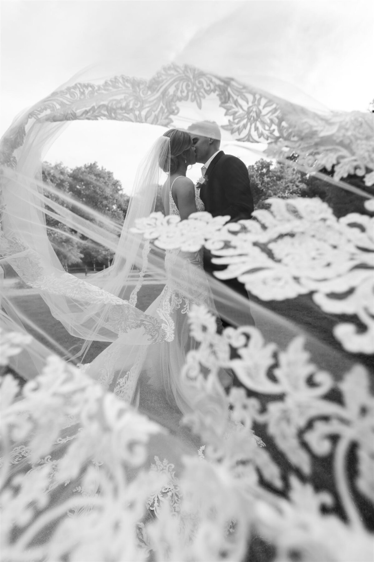 couple kissing framed by lace veil blowing in the wind