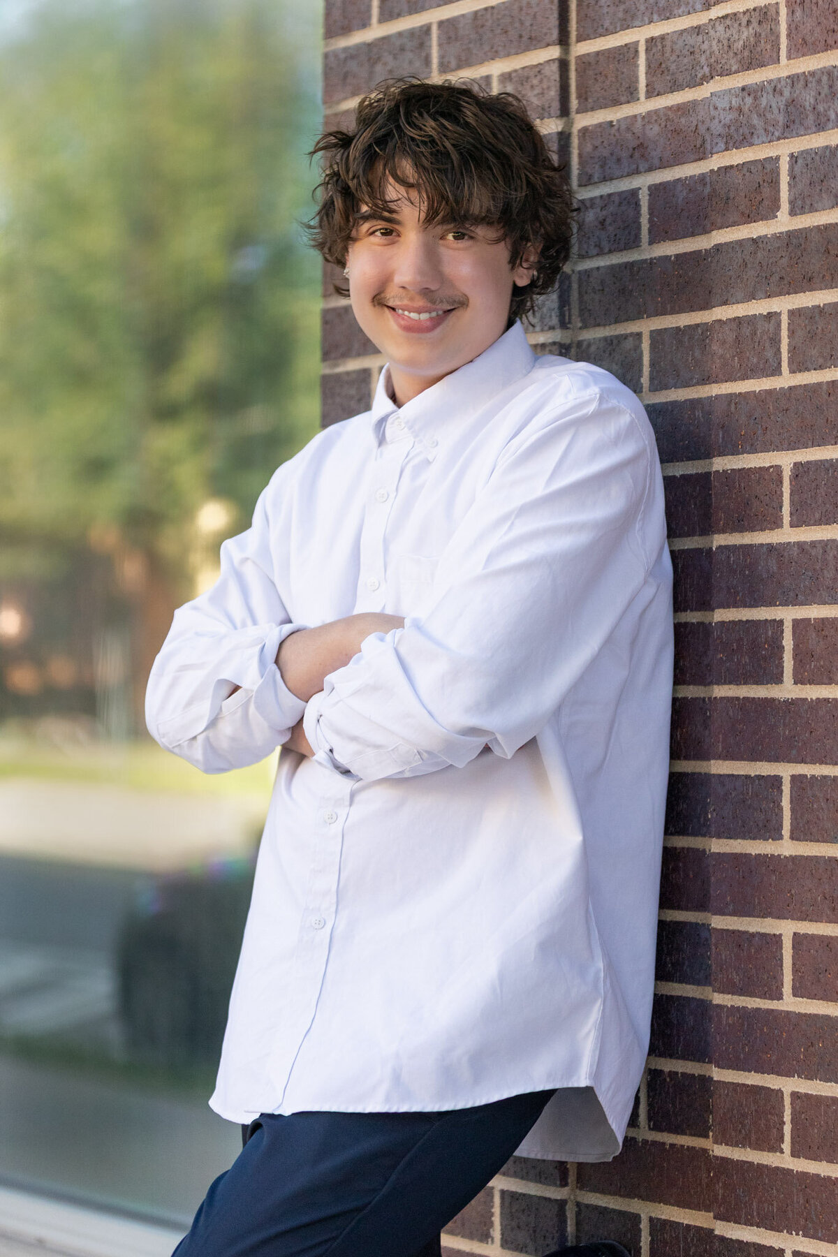 A senior guy leaning against a brick wall in Lawrence, KS