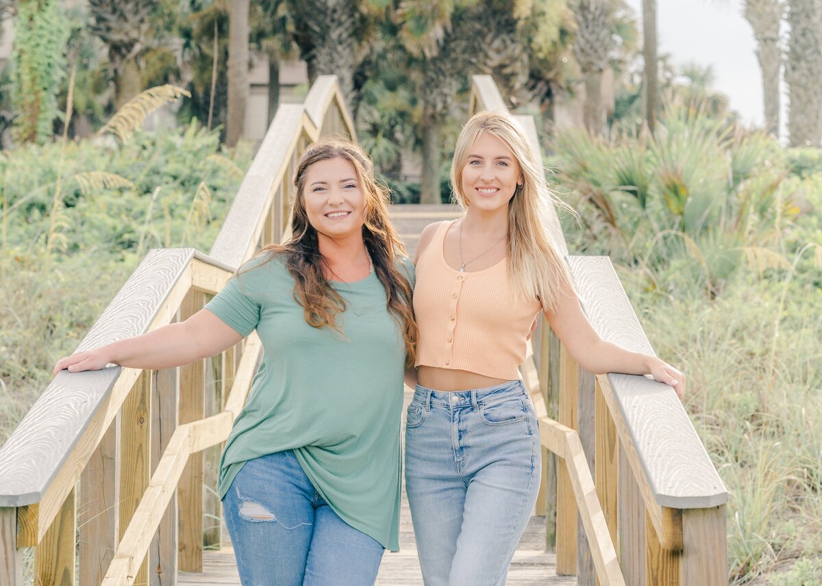 adult sisters hugging on wooden walkway on their beach vacation in florida