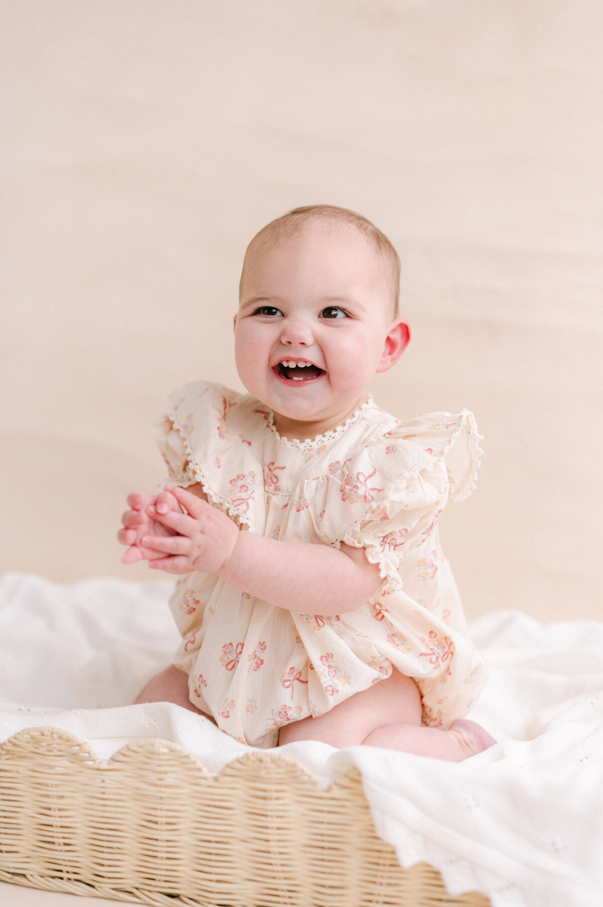 Baby in a feminine ruffle dress clapping her hands and smiling