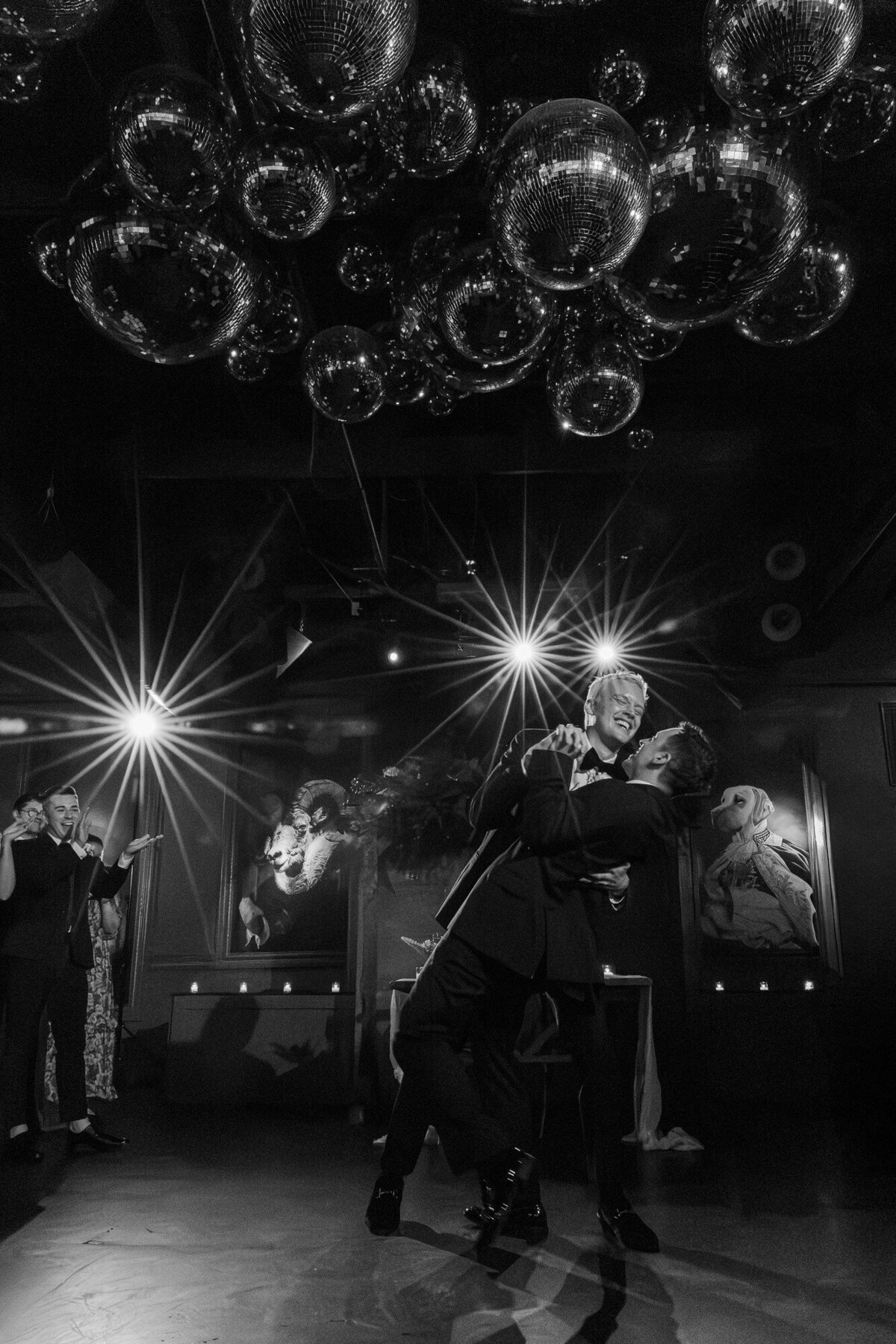 Black and white dance floor photo of a couple surrounded by disco balls and starburst lights