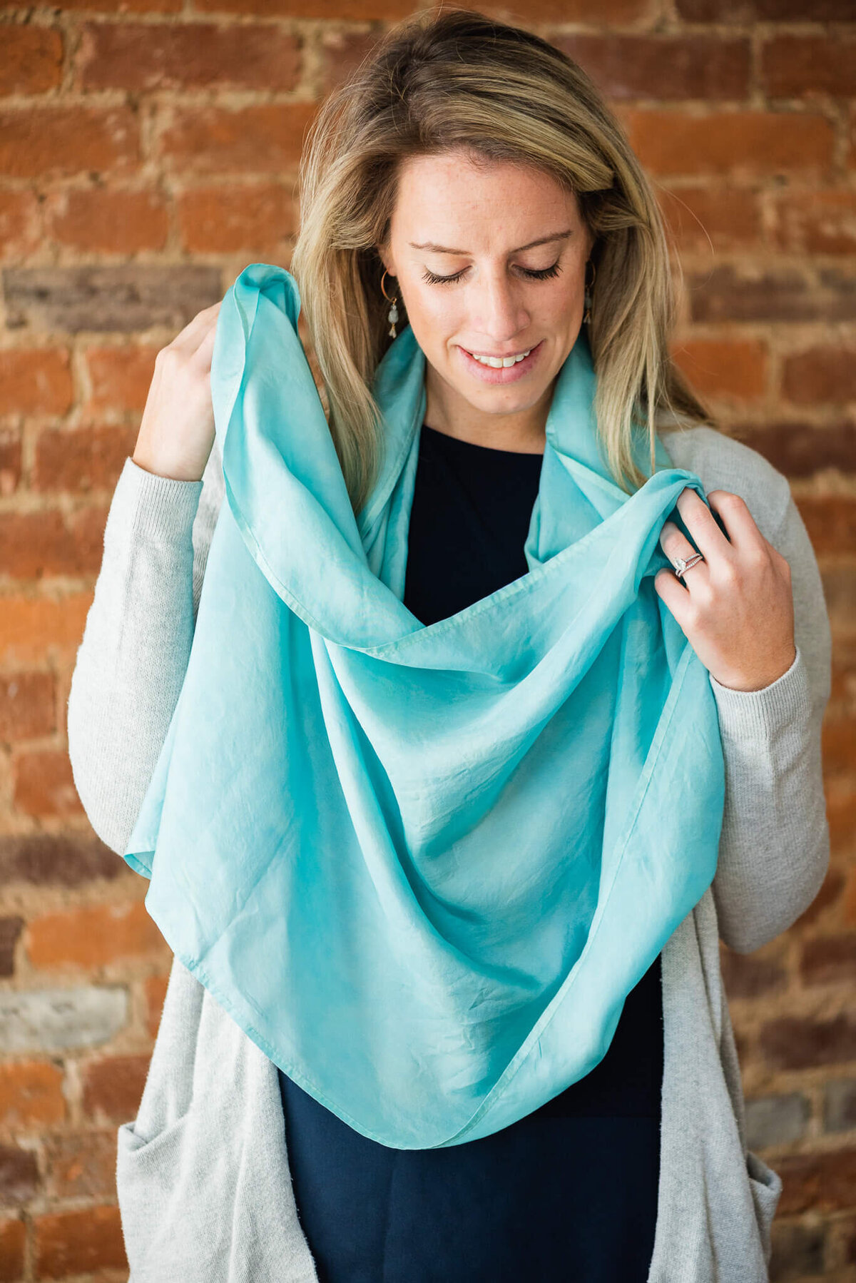 woman draping a light blue infinity silk scarf around neck