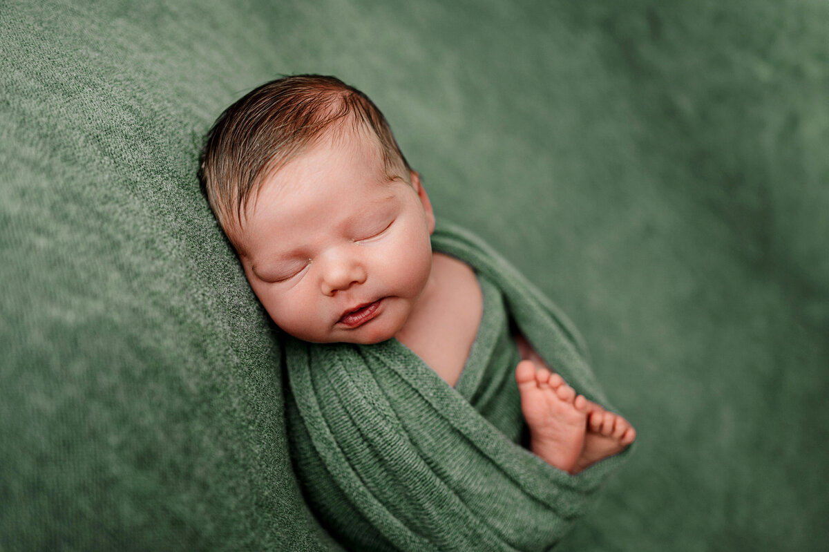 baby boy in green during safe and relaxing newborn baby studio photography session
